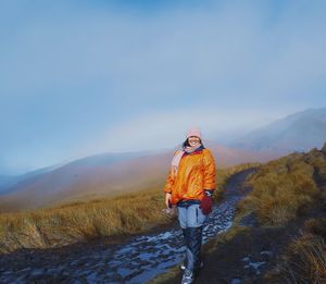 Portrait of smiling woman standing on mountain against sky