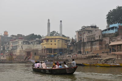 Boats in canal amidst buildings in city against sky