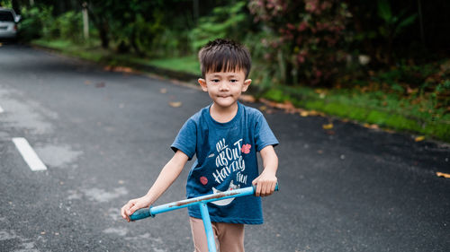 Boy riding push scooter on road