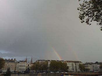 Rainbow over buildings in city against sky