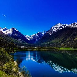 Scenic view of lake and mountains against blue sky