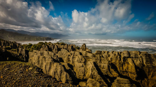 Scenic view of pancake rocks by sea against sky