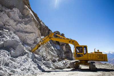 Earth mover at construction site against sky