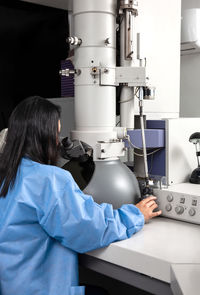 Young female scientist working at the laboratory with an electron microscope