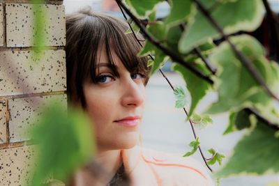 Portrait of woman by wall seen through plants