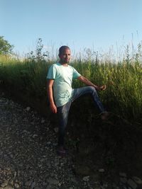 Young man standing on field against sky