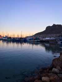 Boats in calm sea against clear sky