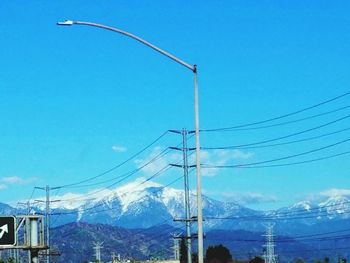 Low angle view of electricity pylon against blue sky