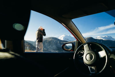 Man photographing seen through car window