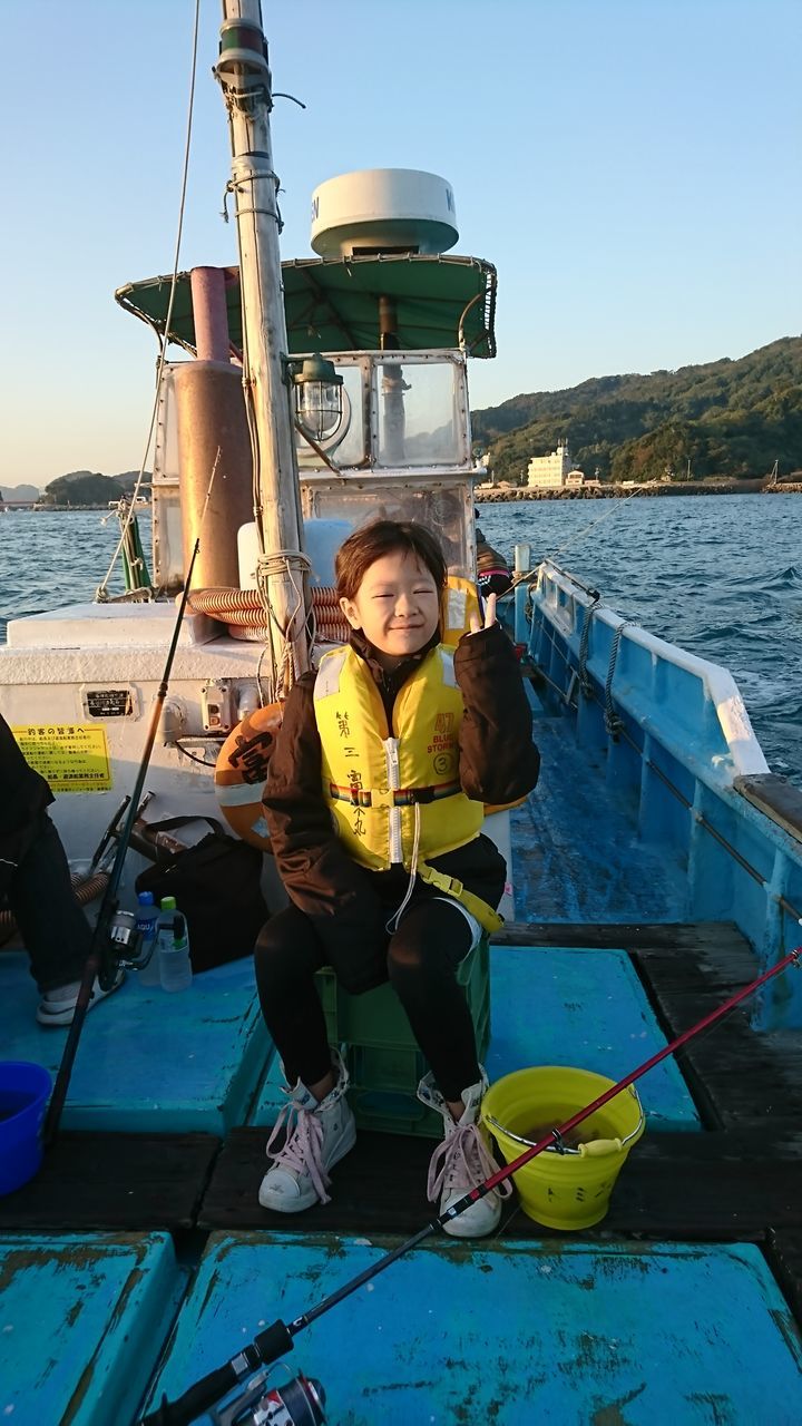 PORTRAIT OF WOMAN SITTING ON BOAT MOORED IN RIVER