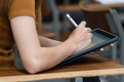 Midsection of man using mobile phone on table