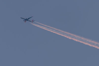 Low angle view of airplane in flight against blue sky