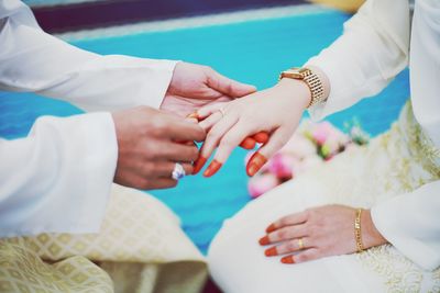Midsection of groom putting ring to bride during wedding ceremony