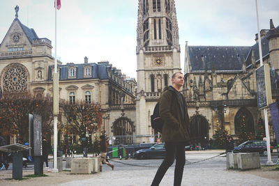 Man standing by historic building in city against sky