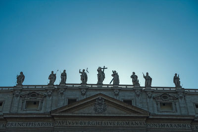 Low angle view of statues against clear blue sky