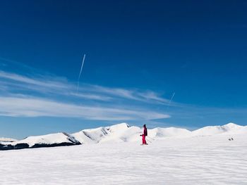 Woman skiing on snow covered land against sky