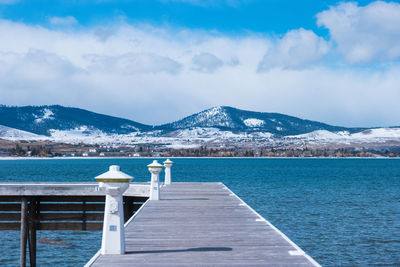 Scenic view of sea by snowcapped mountains against sky