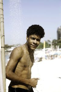 Side view of shirtless man bathing at beach during summer