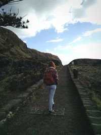 Rear view of woman standing on mountain against sky