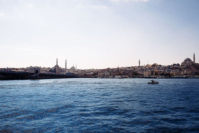 View of buildings by river against sky in city