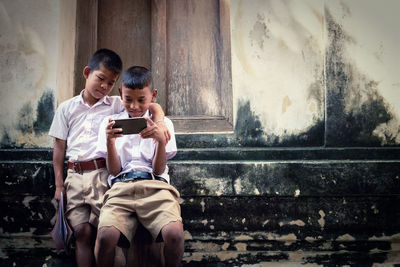 Male students using phone by building