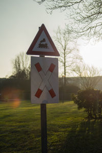 Close-up of road sign on field against sky