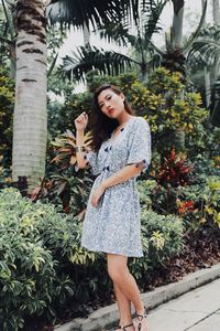 Portrait of young woman standing against plants