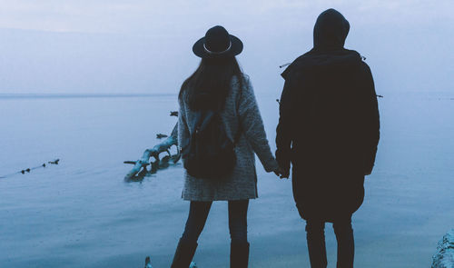 Rear view of couple by the sea against sky