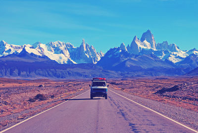 Road amidst snowcapped mountains against sky