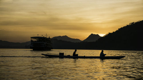 Silhouette boats in lake against sky during sunset