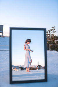 Woman standing with umbrella against clear sky