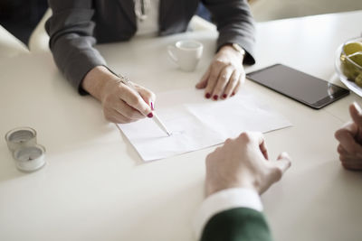 Cropped image of businesswoman drawing while explaining colleague at desk