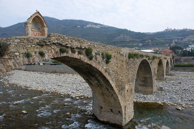 Arch bridge over buildings against sky