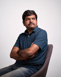 Young man sitting against white background