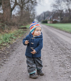 Cute girl looking away while walking on dirt road