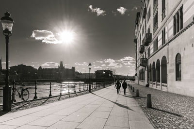 2 silhouettes walking on the quayside in backlight, black and white