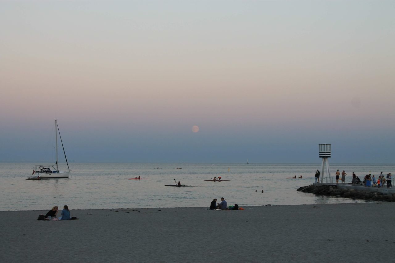 GROUP OF PEOPLE ON BEACH AGAINST SKY