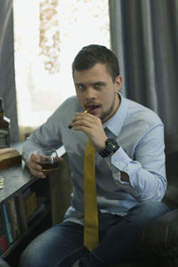 Man holding cigarette while sitting on table