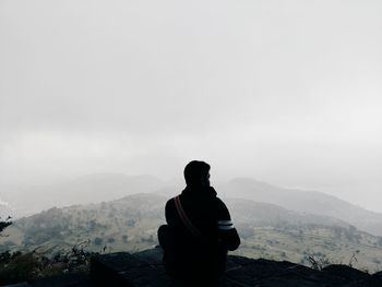 Man looking at mountains against sky