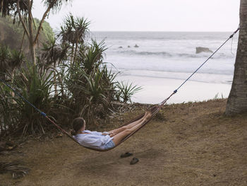 Woman relaxing on hammock at ocean coastline