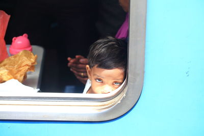 Close-up of young man looking through window