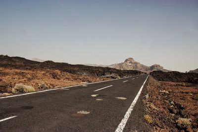 Road by mountains against clear sky