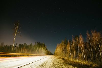 Road amidst trees against clear sky at night