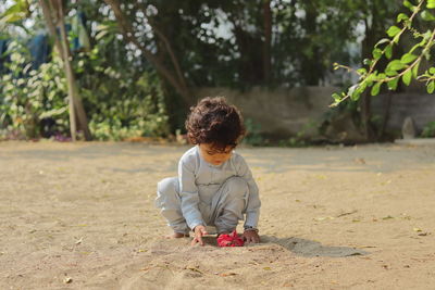 Full length of cute boy sitting on land