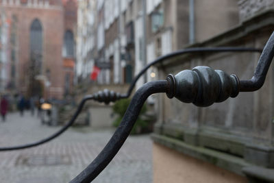 Close-up of metal railing on street against buildings