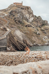 Woman on rock formation against sky