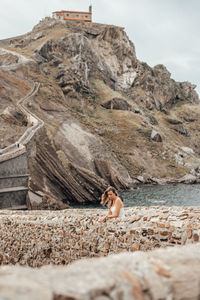 Woman on rock formation against sky