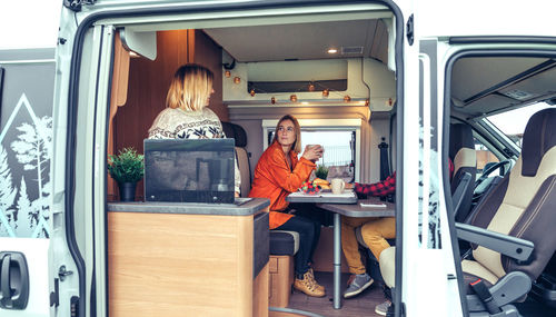 Friends having breakfast in a camper van in the morning