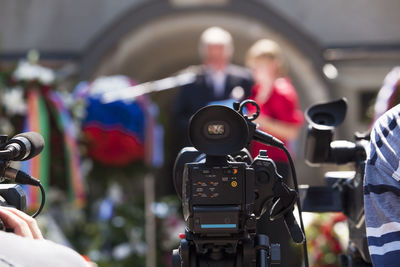 Close-up of camera against people