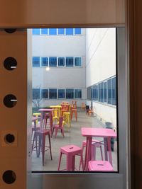 Chairs and tables in building seen through glass window